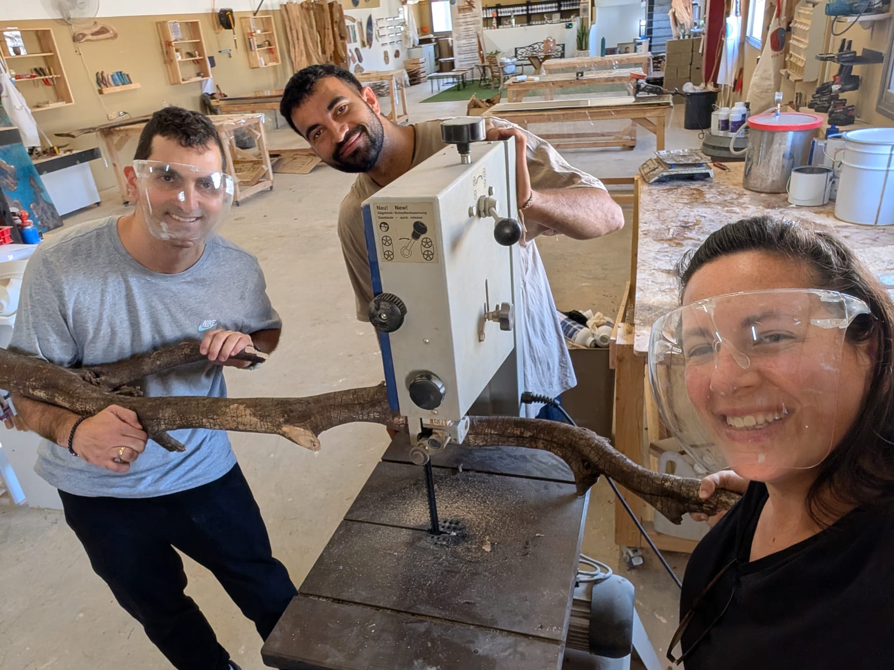 משתתפים חותכים ענף עץ במסור בסדנת מנורות